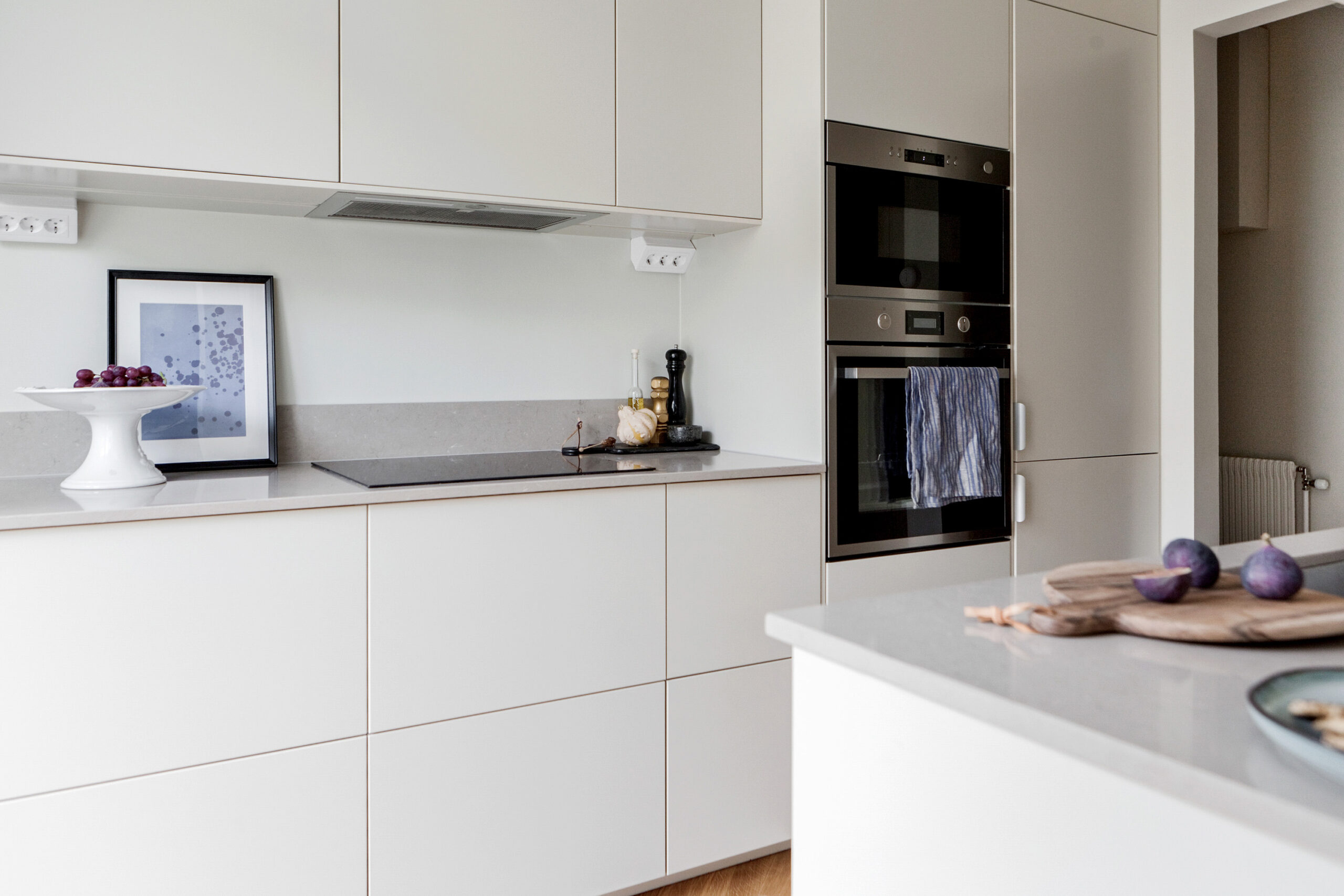 Ett modernt kök med släta vita skåp, inbyggda rostfria apparater och en neutral bakgrundsfärg.